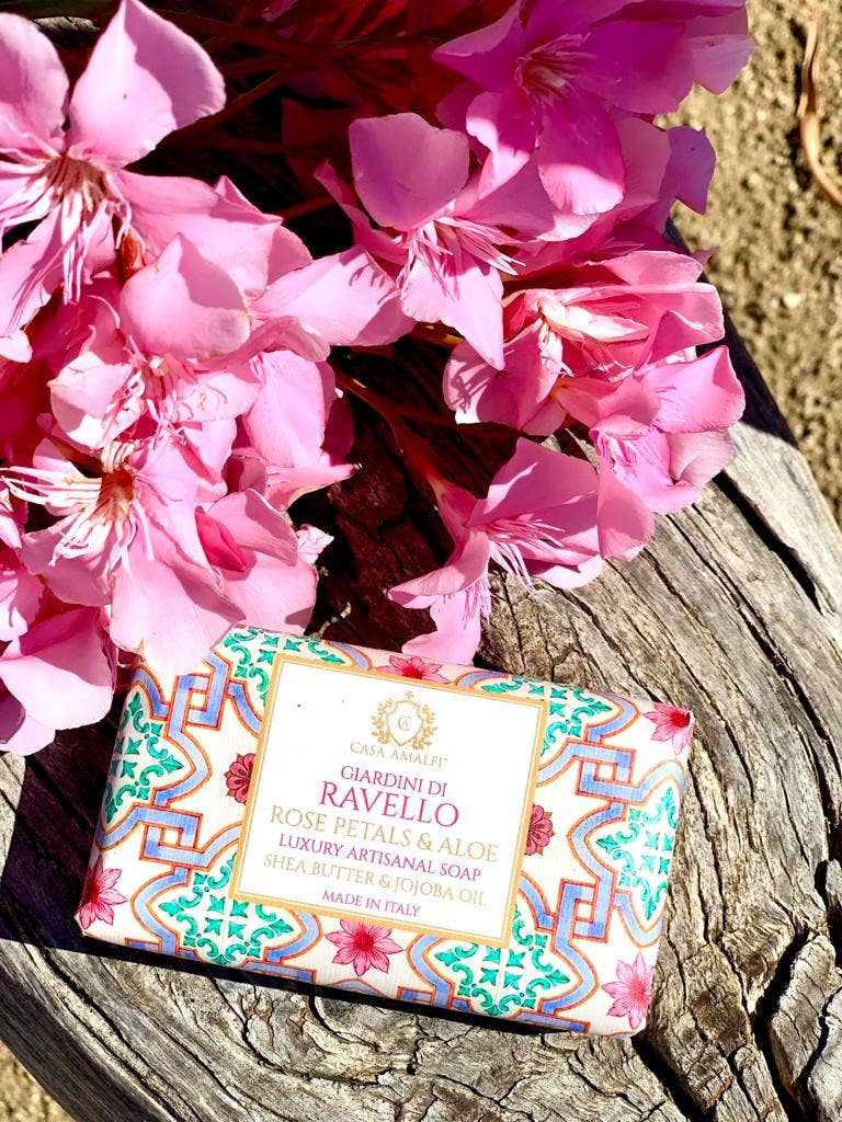 Bar of soap with decorative packaging on a wooden surface with pink flowers.