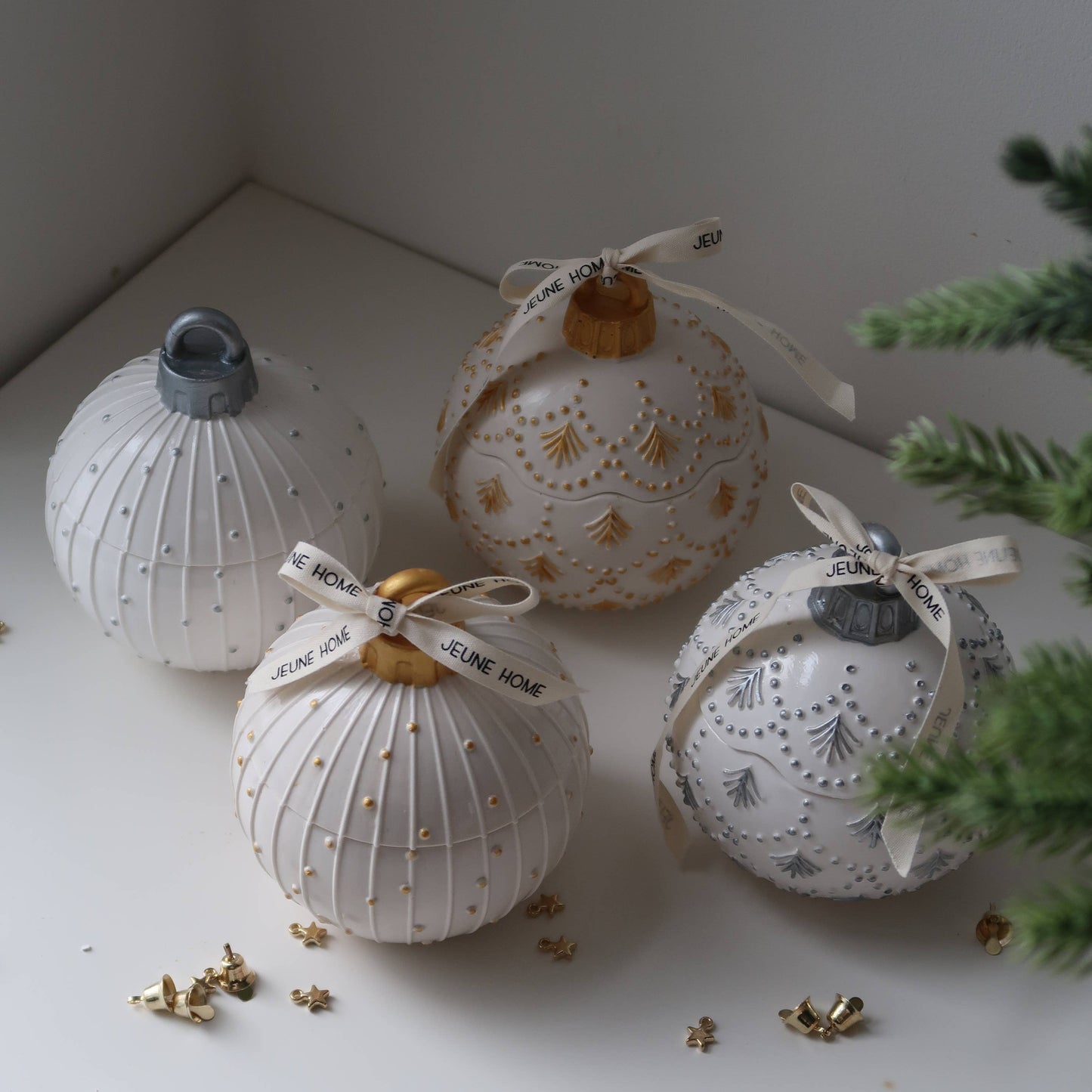 Decorative white ornaments with gold accents on a light surface with greenery.
