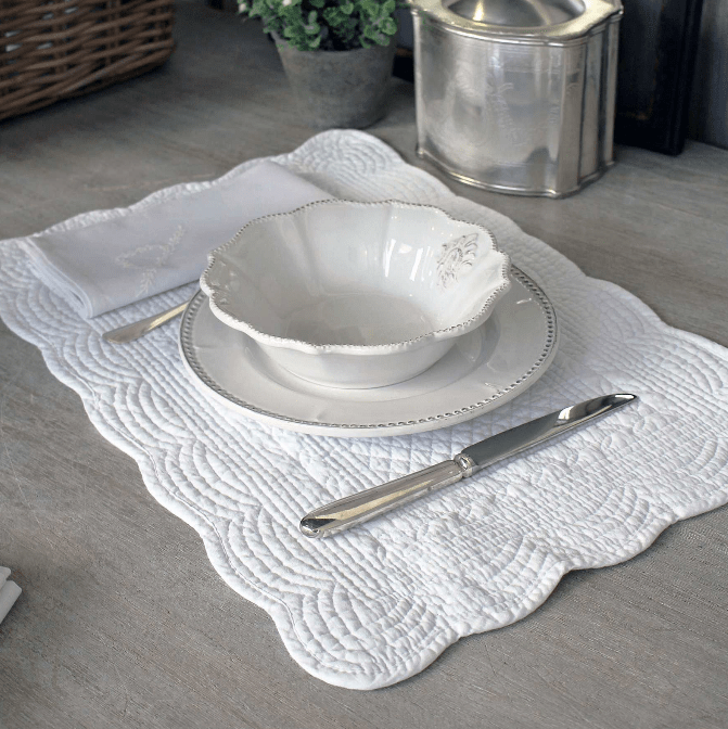 White lace placemat on a wooden table with a plate and cutlery.