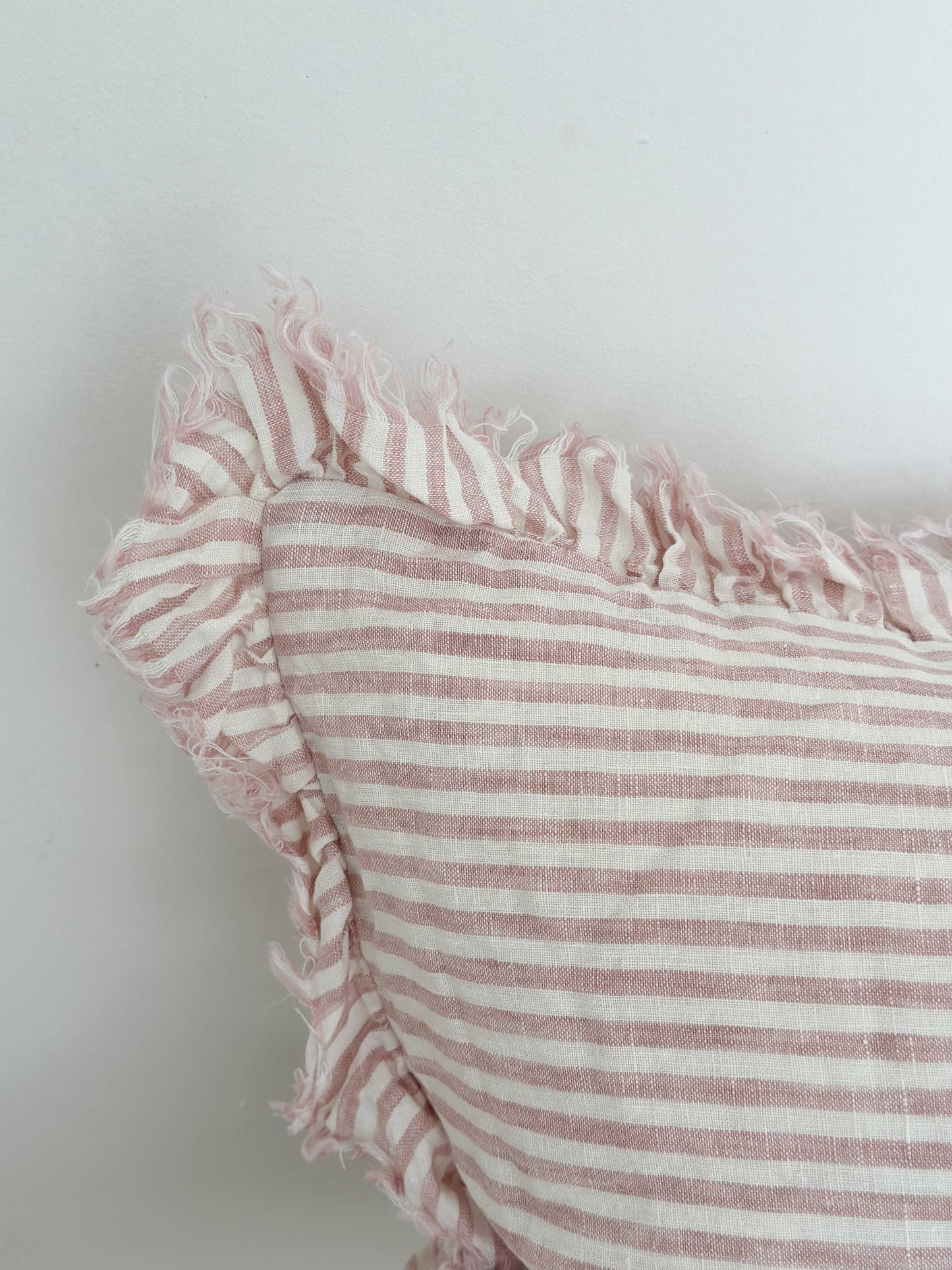 Close-up of a pink and white striped fabric with ruffled edge on a light background