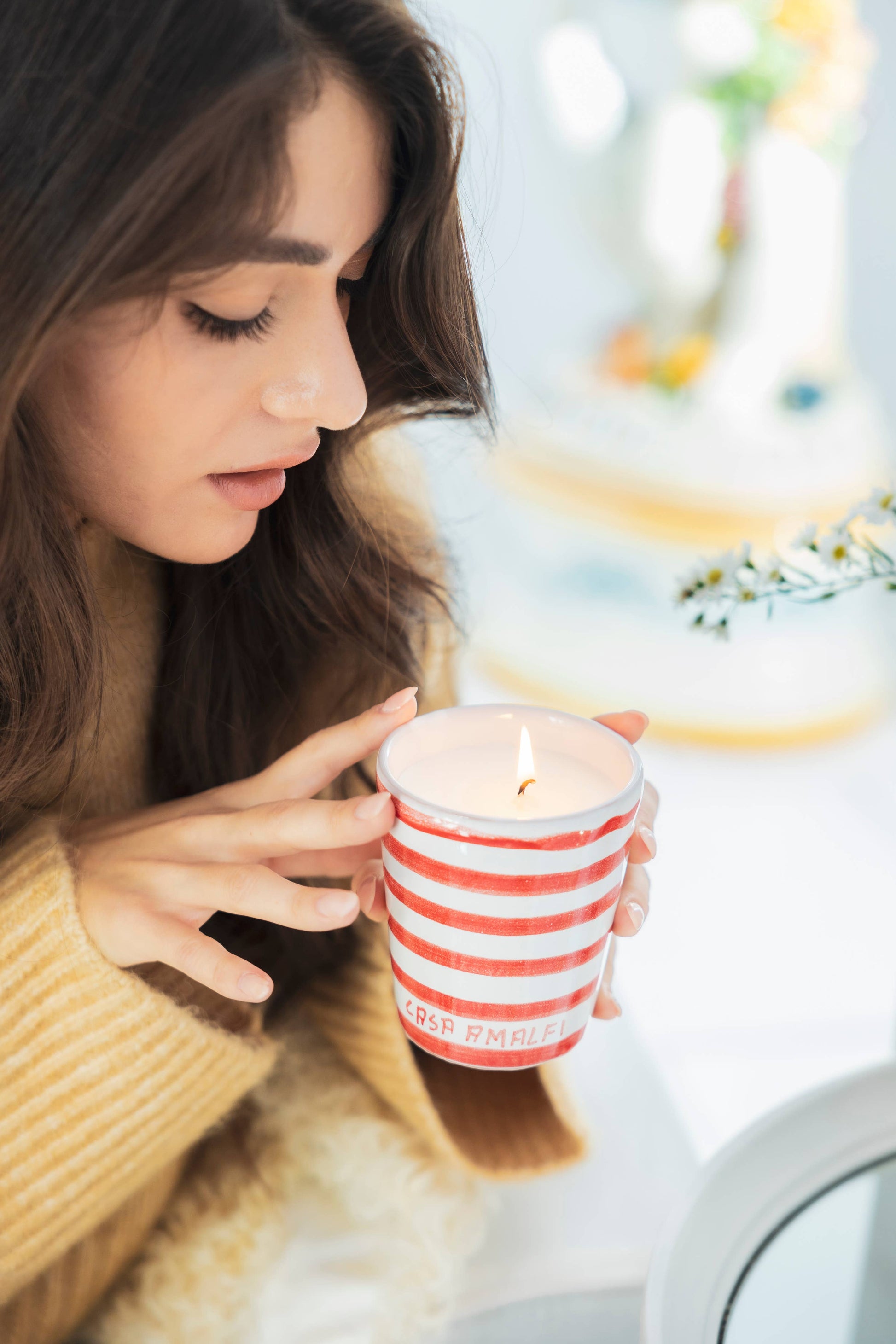 Woman holding a striped candle close to her face with a blurred background