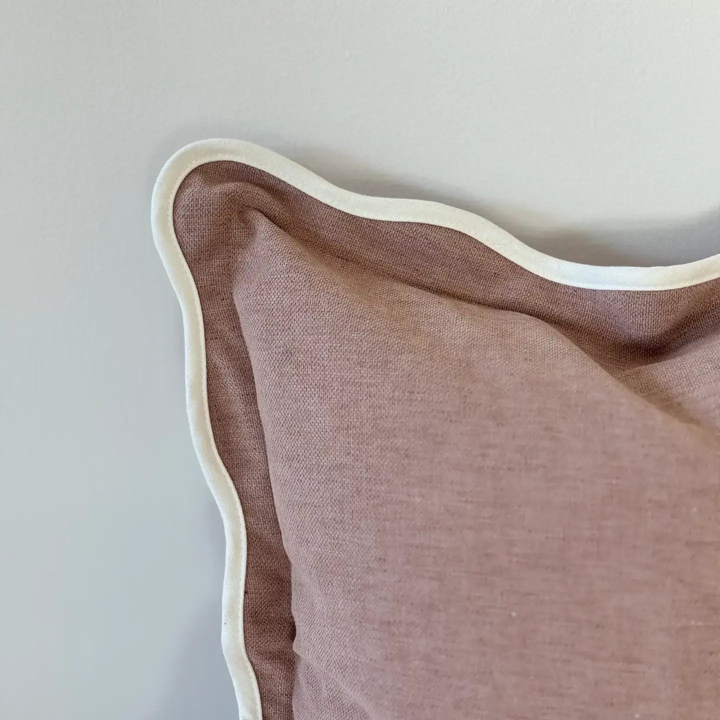 Brown pillow with beige trim on a light gray background