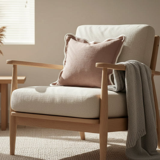A large 65cm square cushion in dusty pink with a wavy scalloped edge detail on a contemporary bed set.
