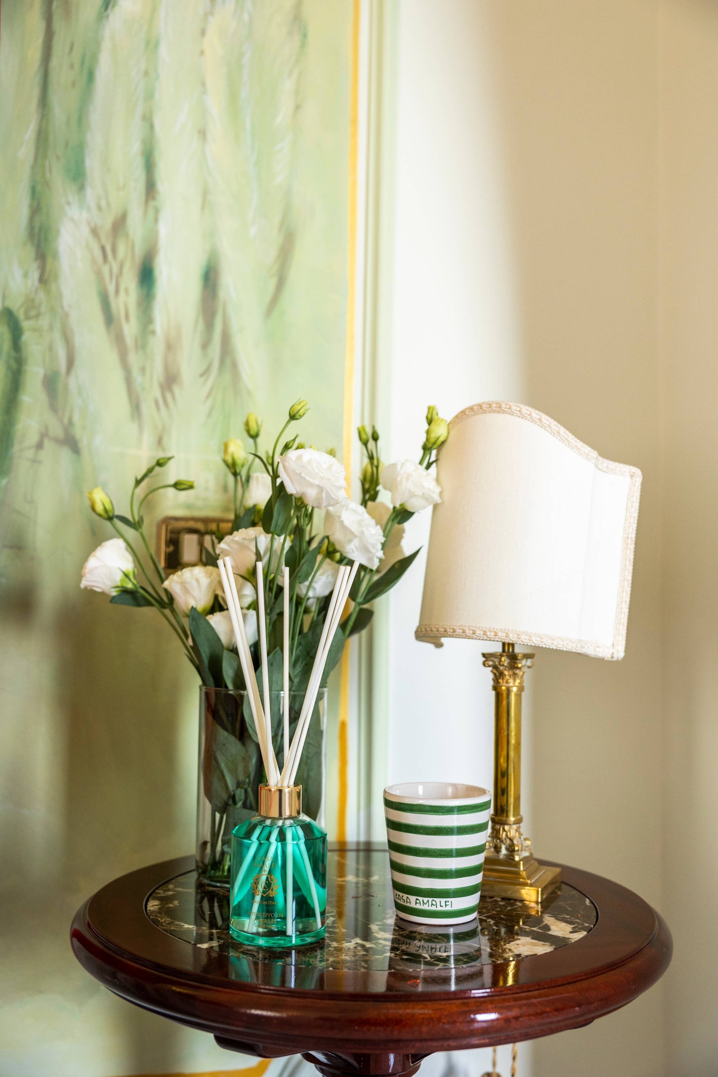 A luxury hand-painted ceramic candle with blue and white stripes, scented with bitter orange and mint, inspired by the Amalfi Coast.