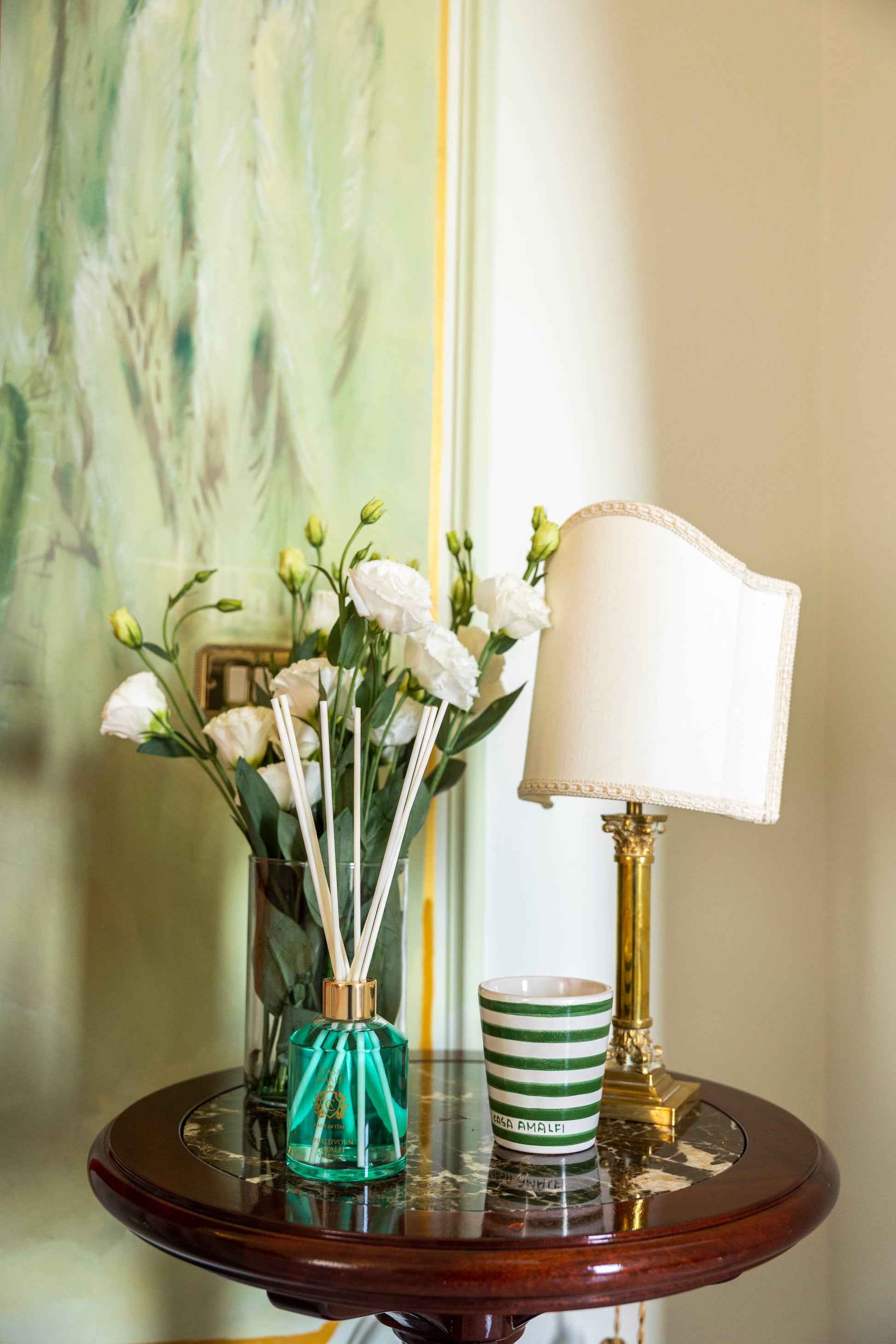 A luxury hand-painted ceramic candle with blue and white stripes, scented with bitter orange and mint, inspired by the Amalfi Coast.