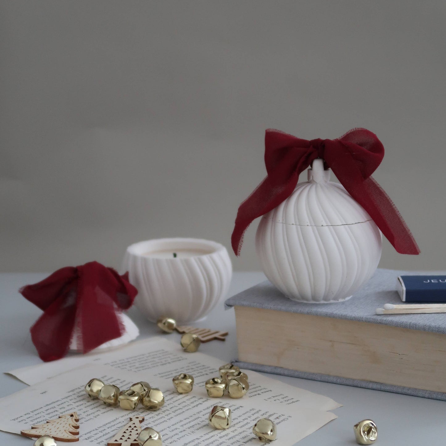 White decorative items with red ribbons on a gray surface with books and small objects.