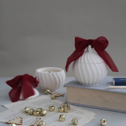 White decorative items with red ribbons on a gray surface with books and small objects.