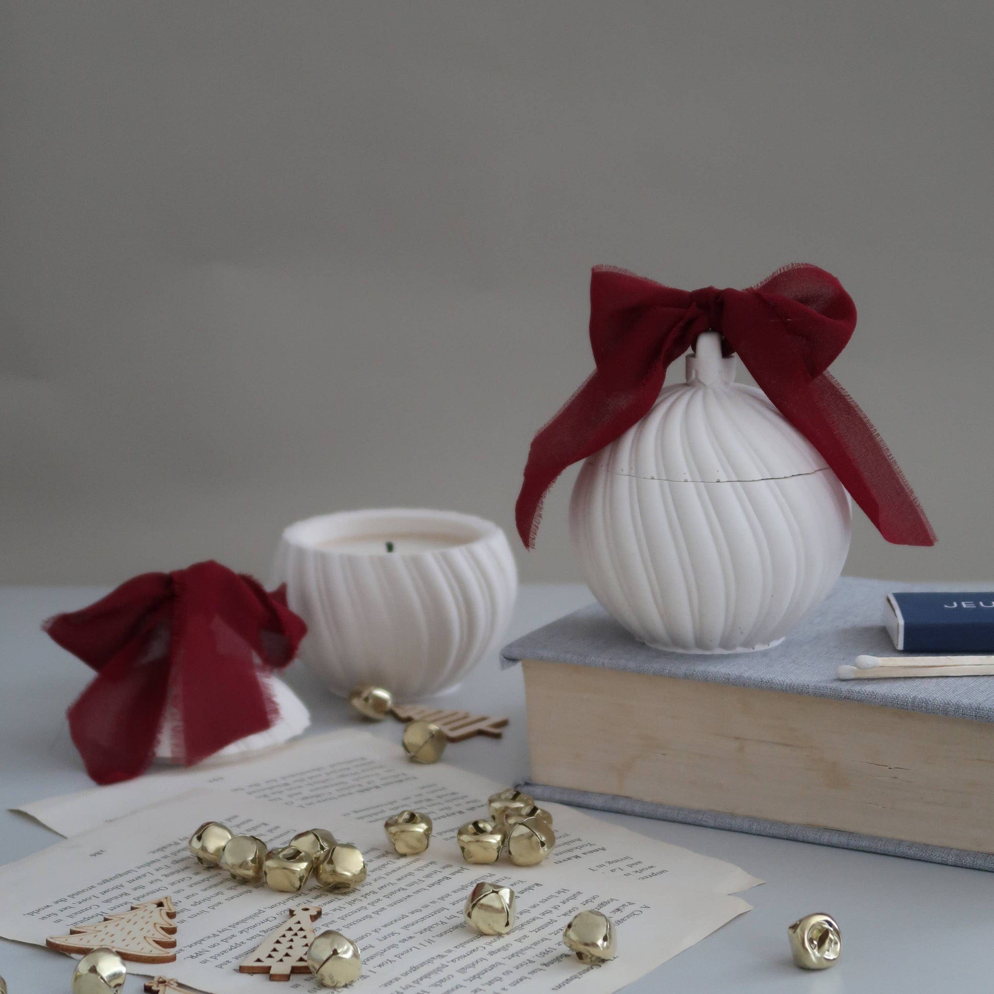 White decorative items with red ribbons on a gray surface with books and small objects.