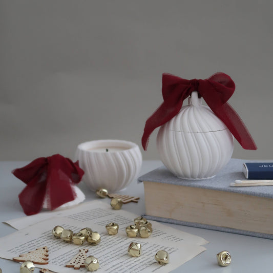 White decorative items with red ribbons on a gray surface with books and small objects.