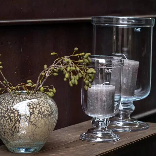 Decorative glassware including a vase and candle holders on a wooden surface with a dark background.