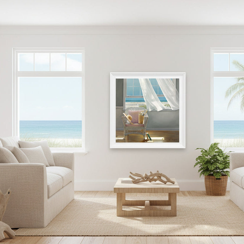 Framed artwork of a wicker chair with a pillow by a window with white curtains.