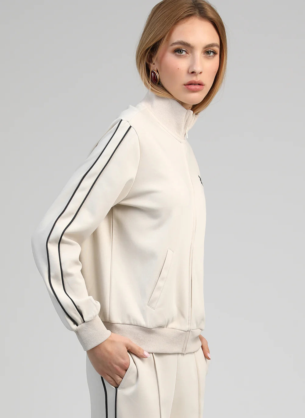 Woman wearing a white outfit with black stripes on a gray background