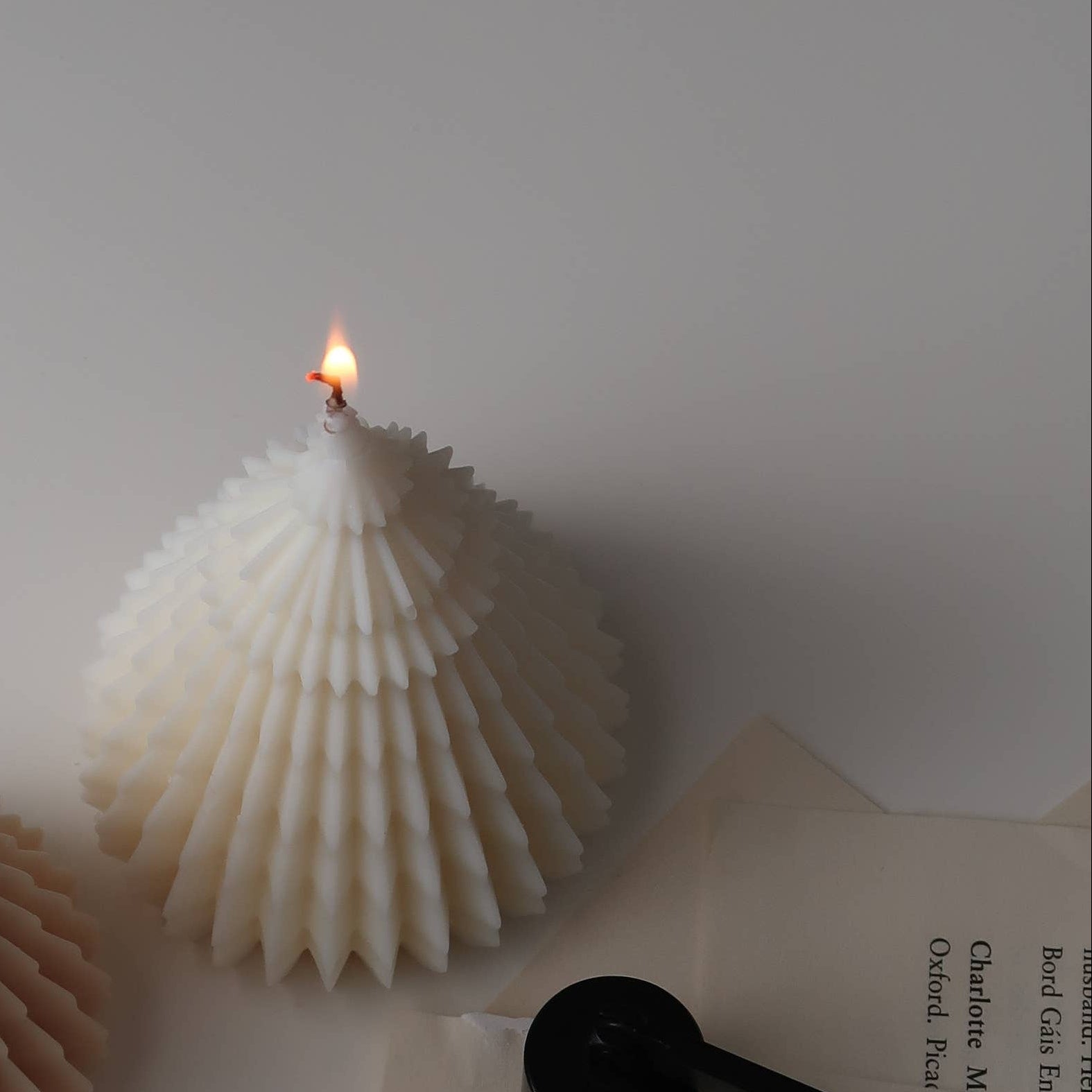 Two shell-shaped candles on a white surface with a book and pen.
