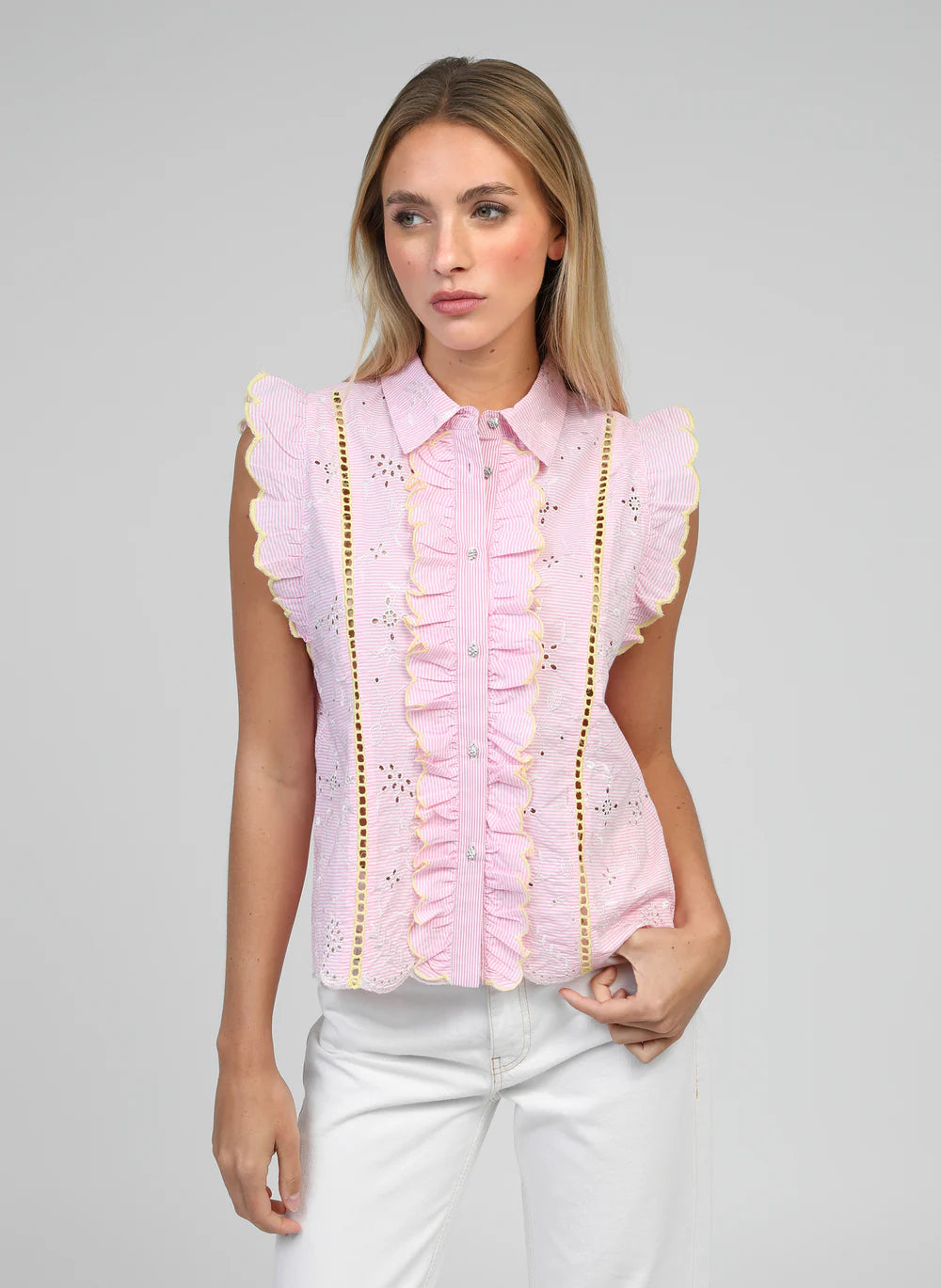 Woman wearing a pink blouse with ruffled details on a gray background
