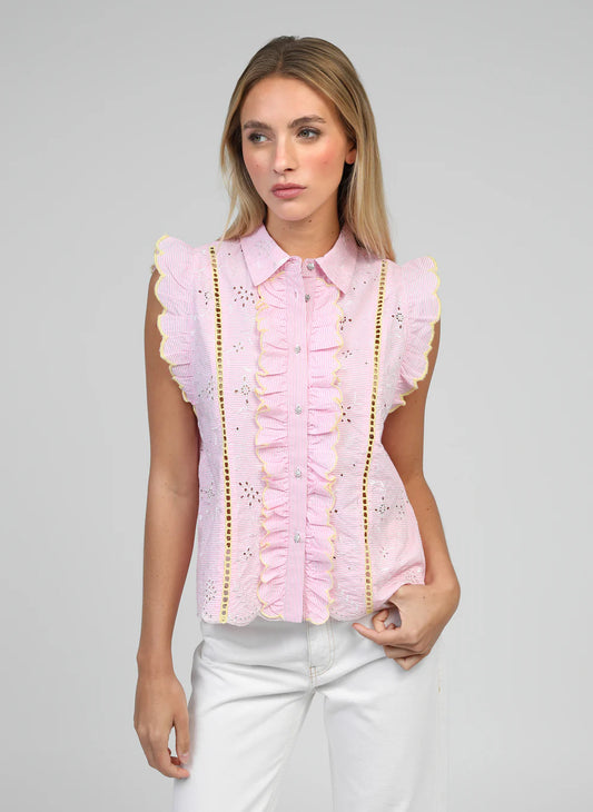Woman wearing a pink blouse with ruffled details on a gray background