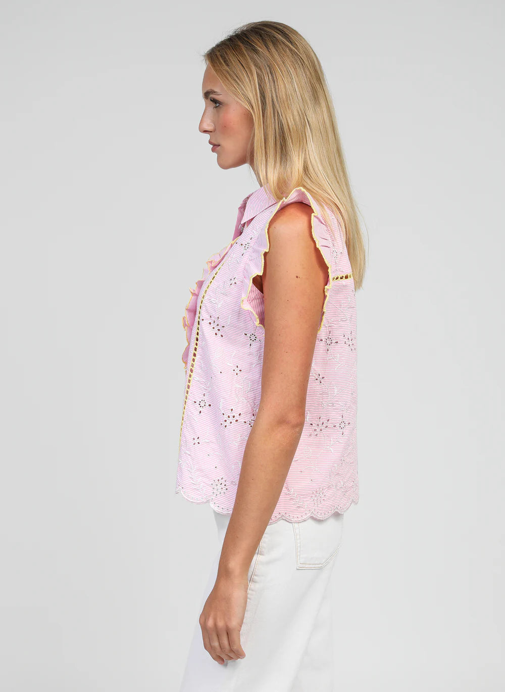 Woman wearing a pink sleeveless top with cut-out details on a plain background