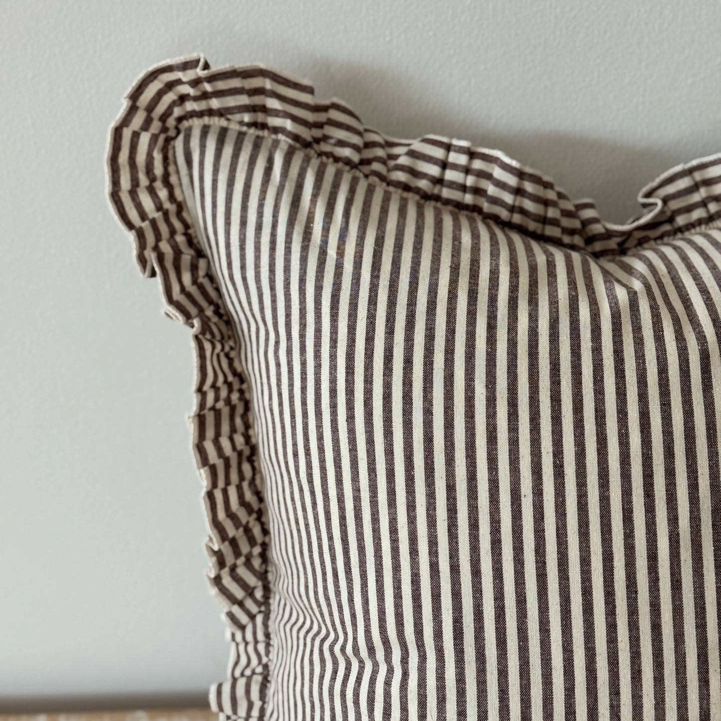 Striped pillow with ruffled edge on a neutral background