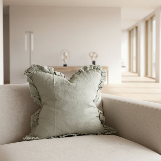 A square 53cm Dusty Sage linen cushion with a ruffled edge, styled on a neutral-toned armchair.
