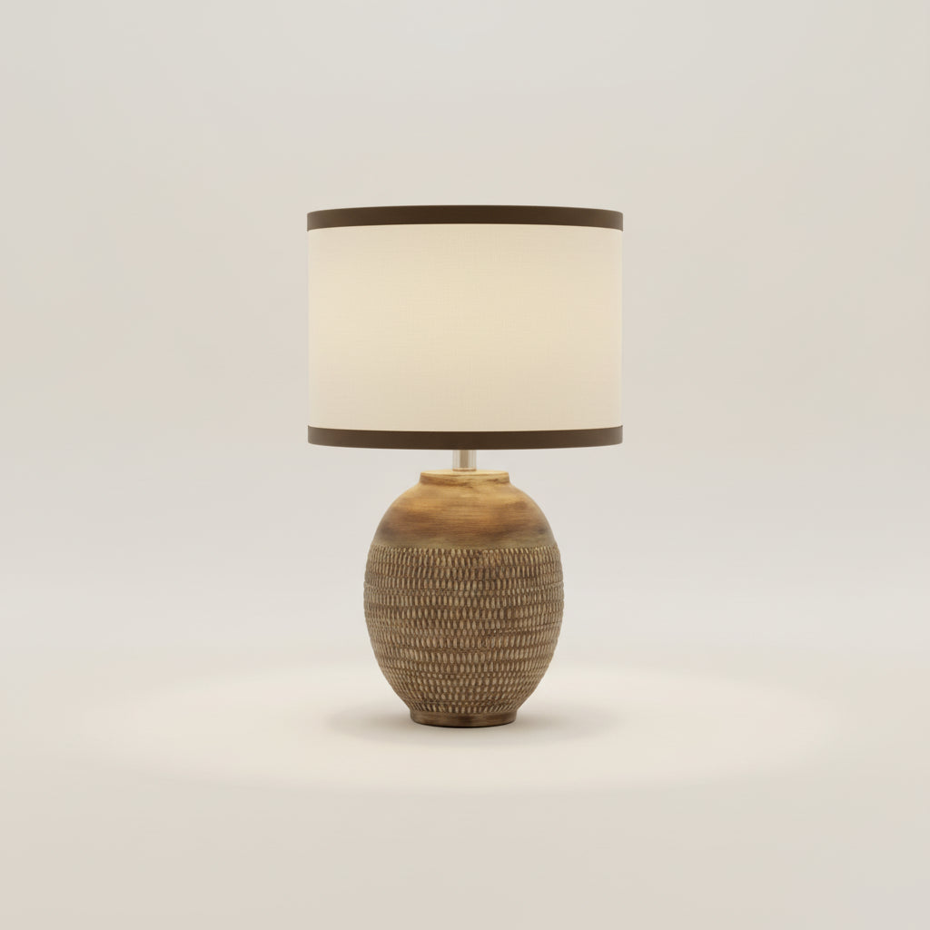 Napoleon Lamp on a bedside table next to an open book and a cup in a cozy bedroom setting.