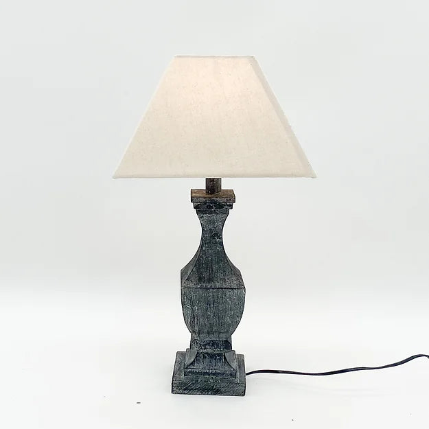 Dark stone table lamp with a tapered, textured base and a white, triangular shade against a white background.