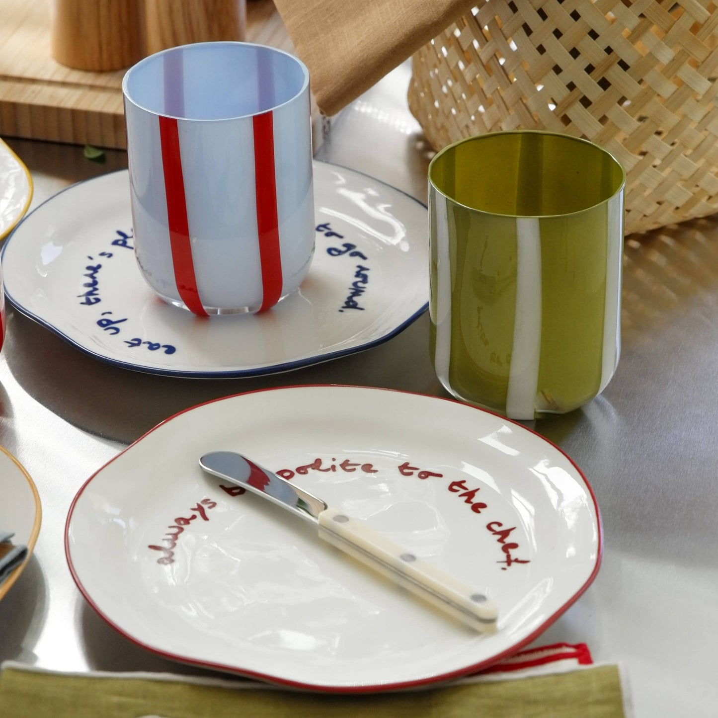 Dinnerware set with cups, plates, and cutlery on a table with decorative napkins.