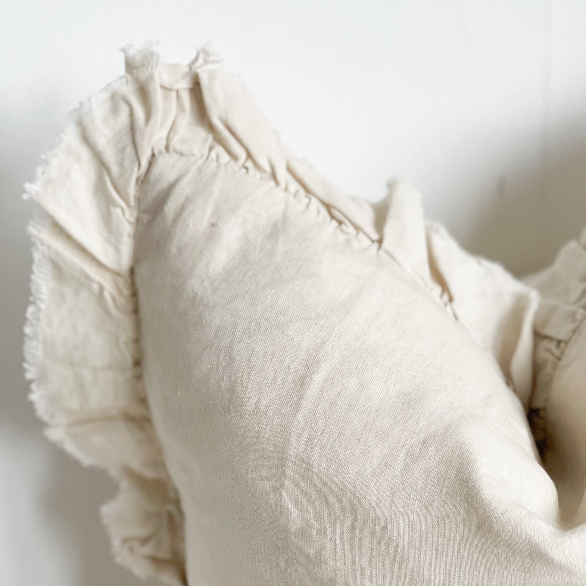 Close-up of a textured white garment with ruffled details on a light background