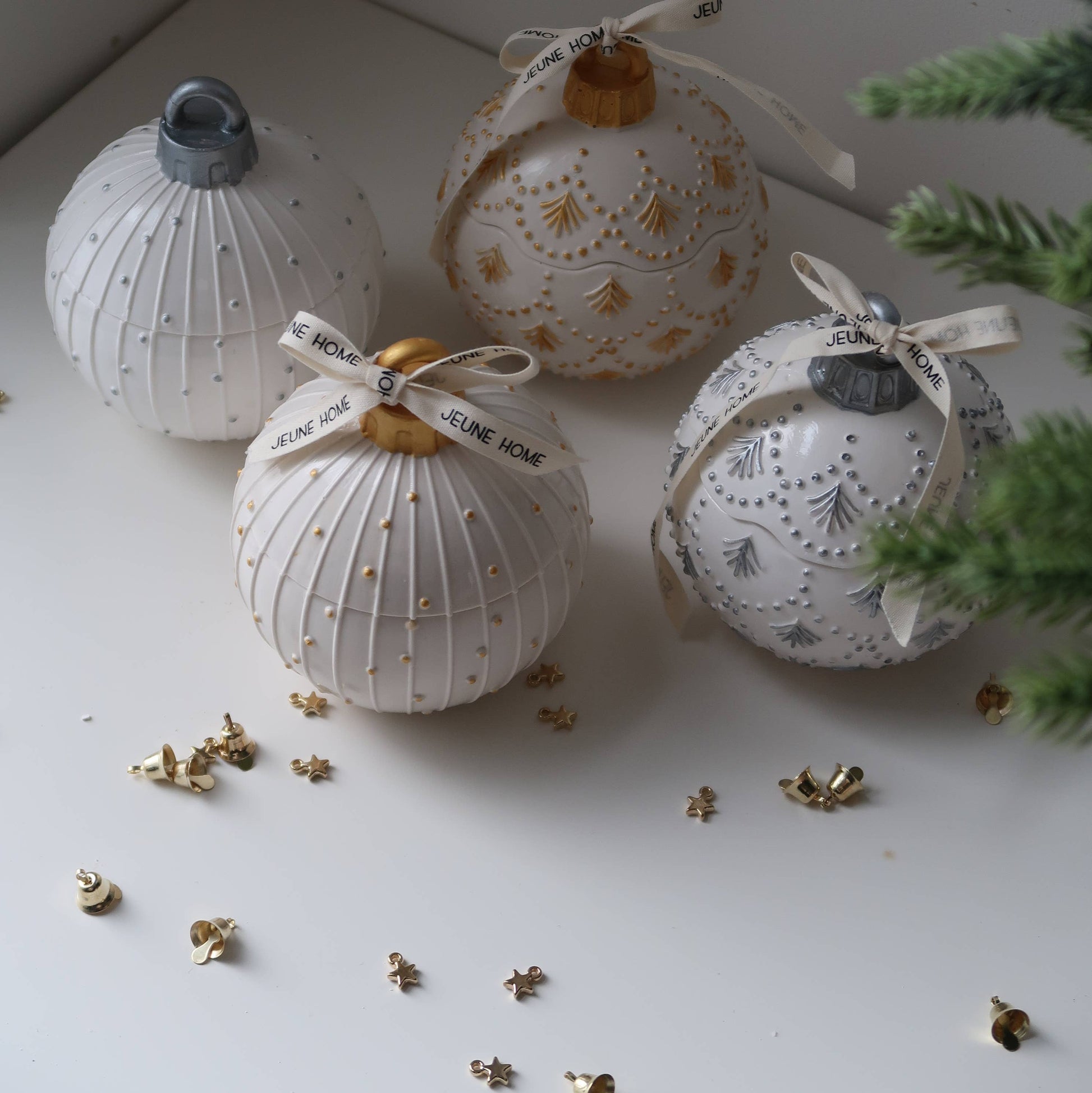 Decorative white ornaments with gold accents on a light surface with greenery.