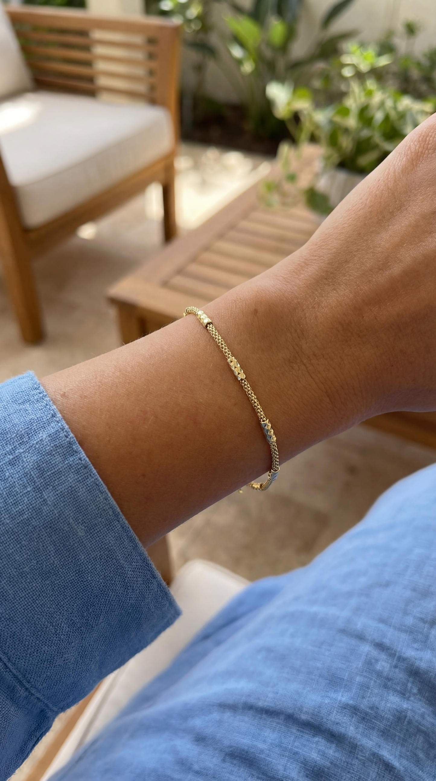 Gold bracelet on a wrist with a blurred outdoor background