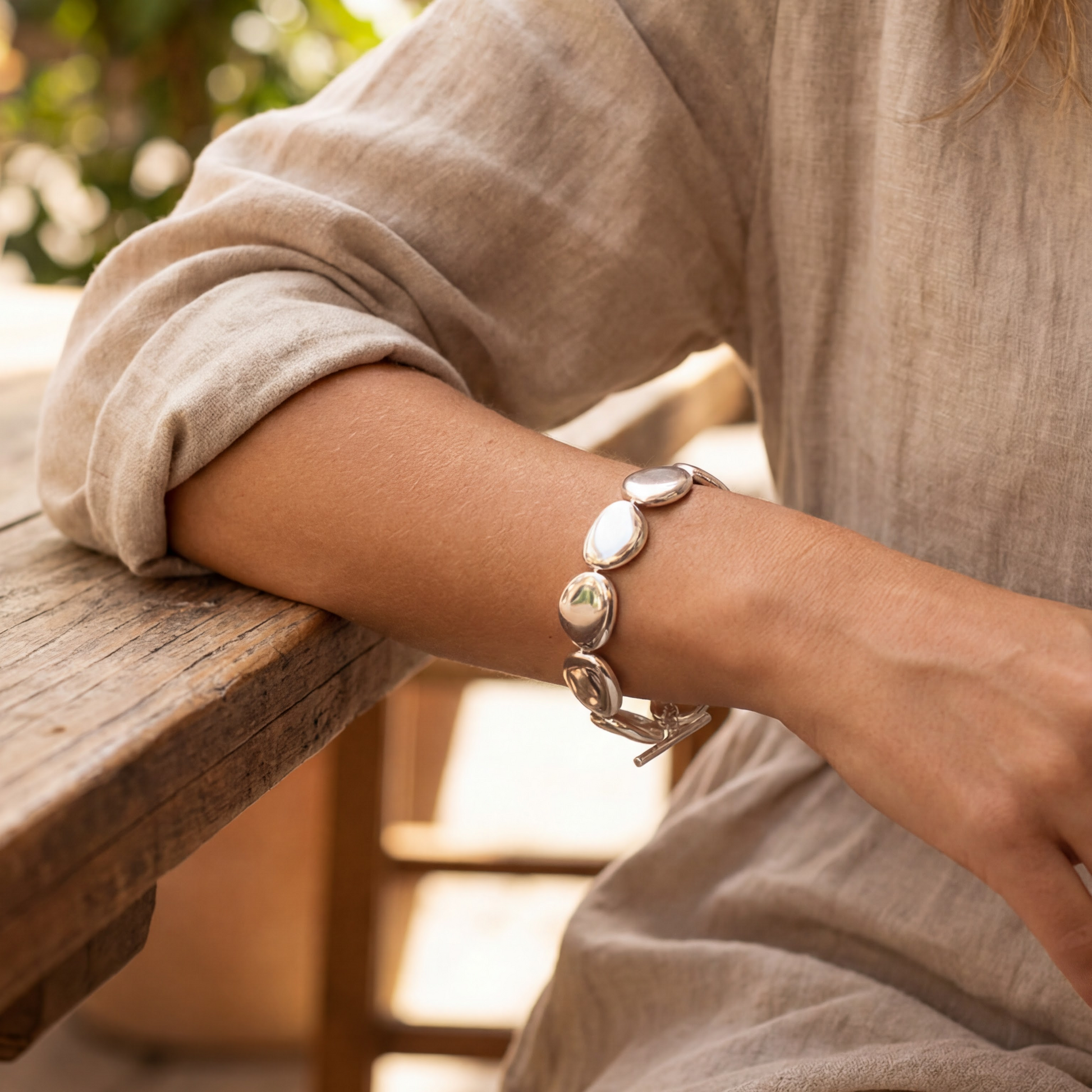 Person wearing a bracelet on a blurred outdoor background