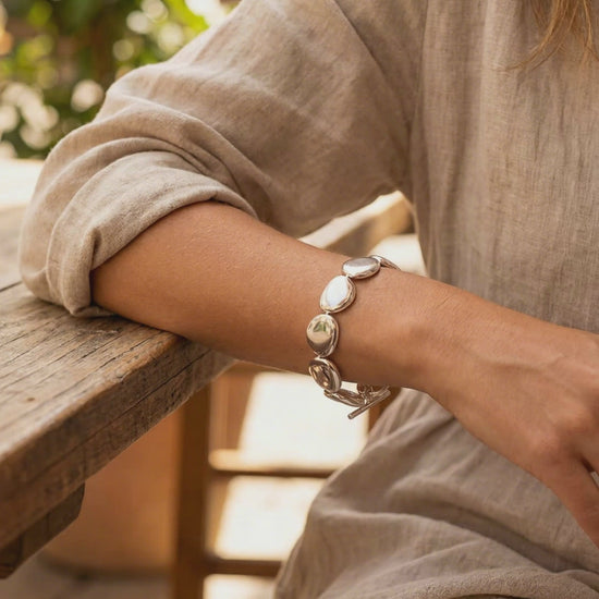 Chunky sterling silver bracelet featuring smooth puffed stone-shaped links and a T-bar toggle clasp on a neutral background.